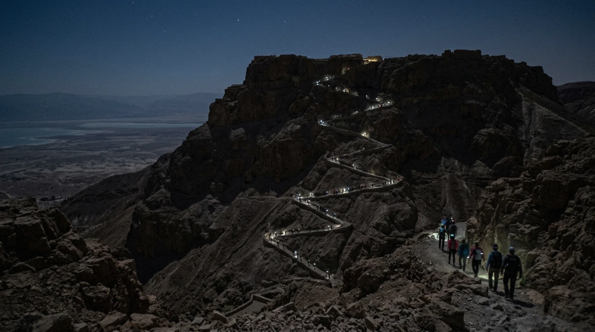 Hikers with headlamps on the Snake Path before dawn on a Masada sunrise tour from Jerusalem