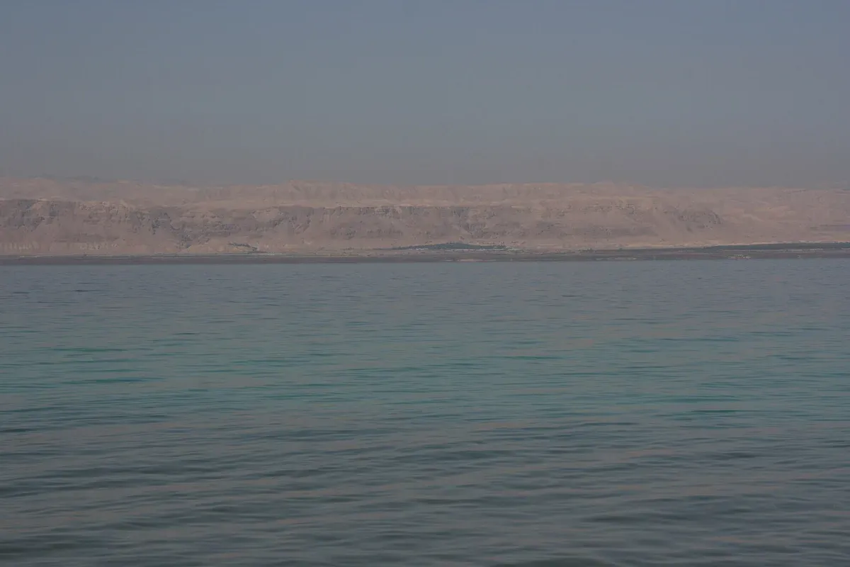 The calm water of the Jordanian shore on a Dead Sea resort day from Amman